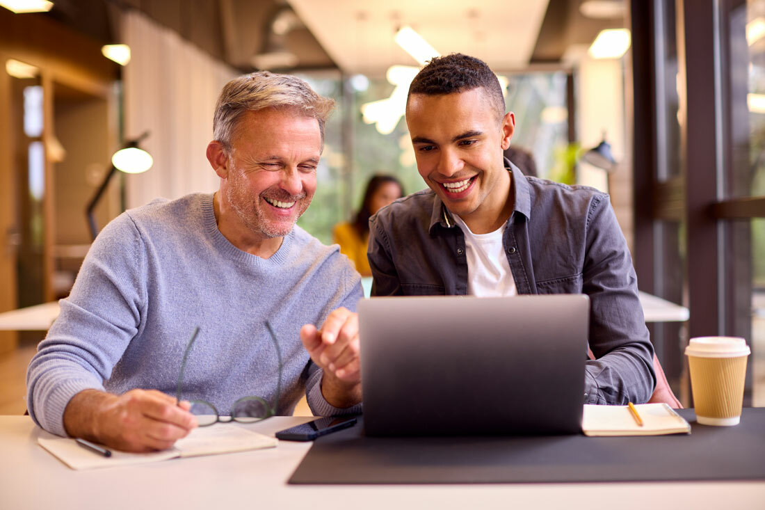 Two men working on something on a laptop together