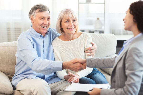 Retired couple talking and shaking hands with their financial advisor.