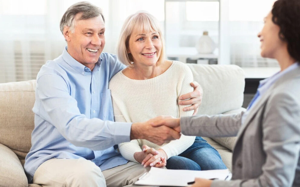 Retired couple talking and shaking hands with their financial advisor.