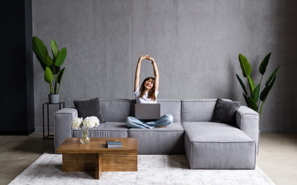 Young woman stretching on her couch after working on her laptop.