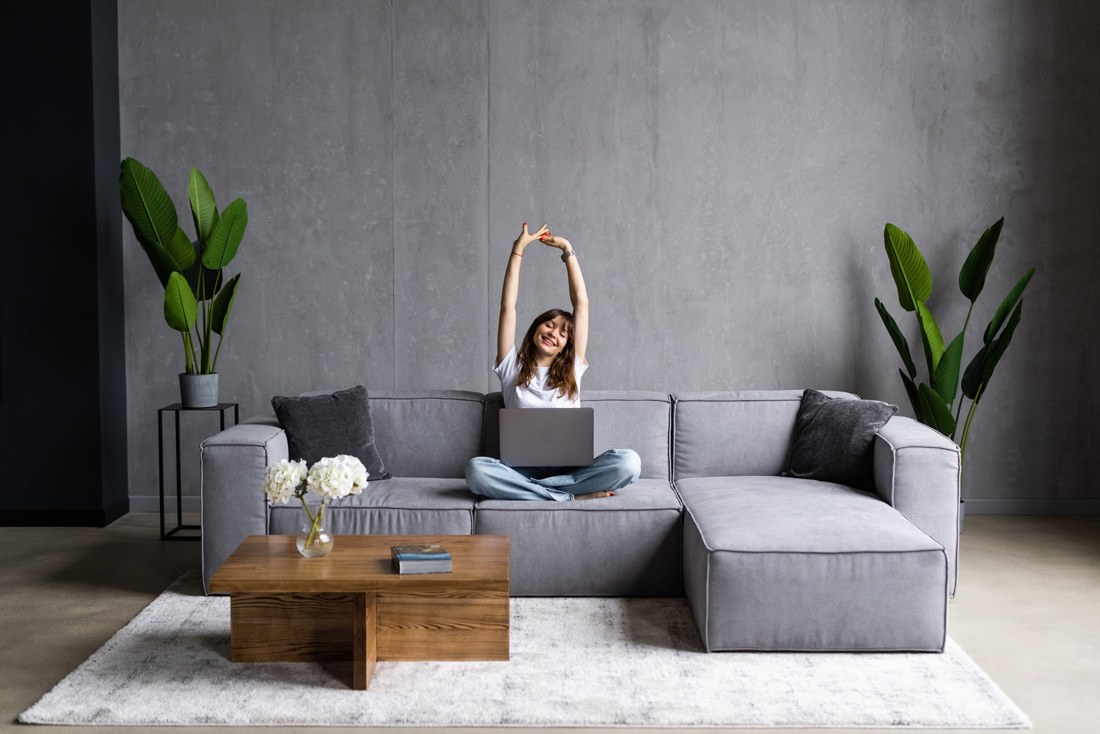 Young woman stretching on her couch after working on her laptop.