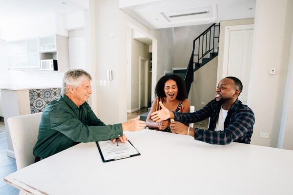 Young couple closing on their new home and shaking hands with their loan officer.