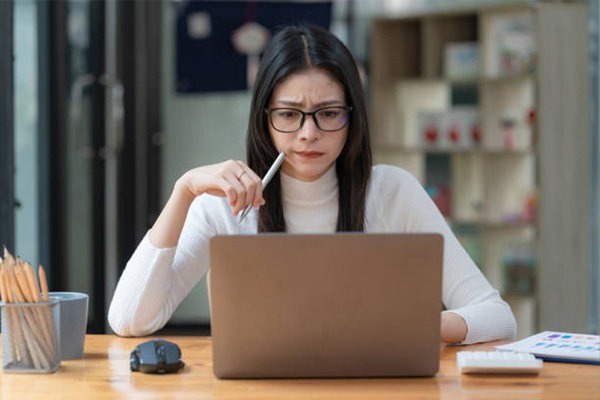 Woman looking puzzled at her laptop.