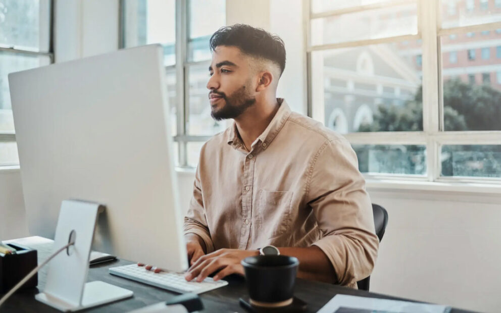 Male looking at his computer at his desk