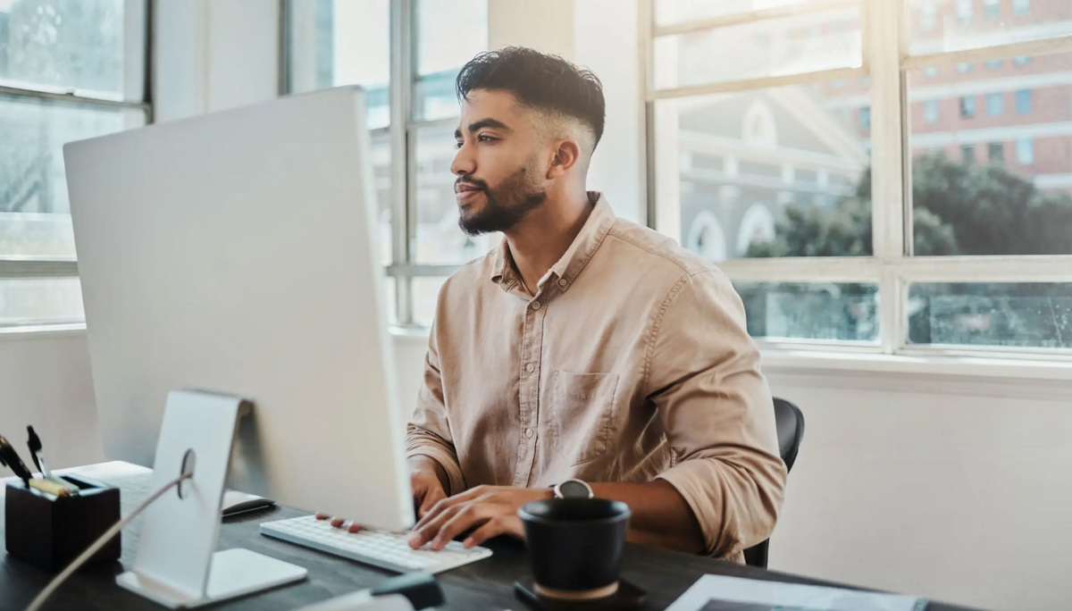 Male looking at his computer at his desk