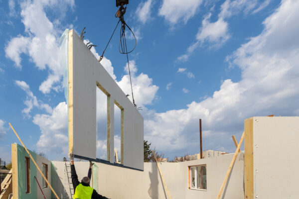 Modular home construction site, with builder navigating a piece of the home down to its right spot from a crane.