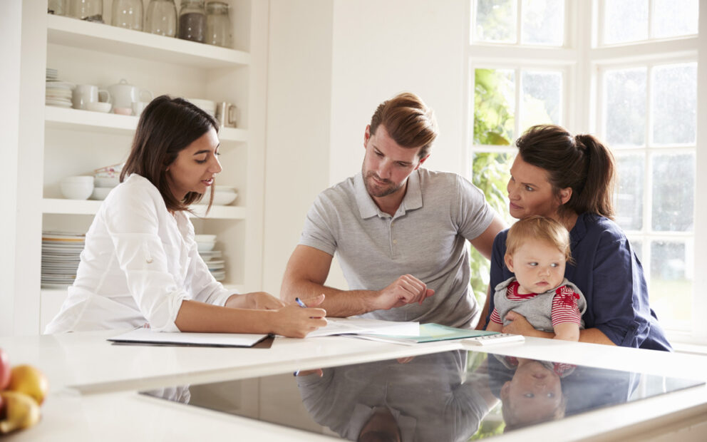 Couple and their baby looking over documents with an advisor