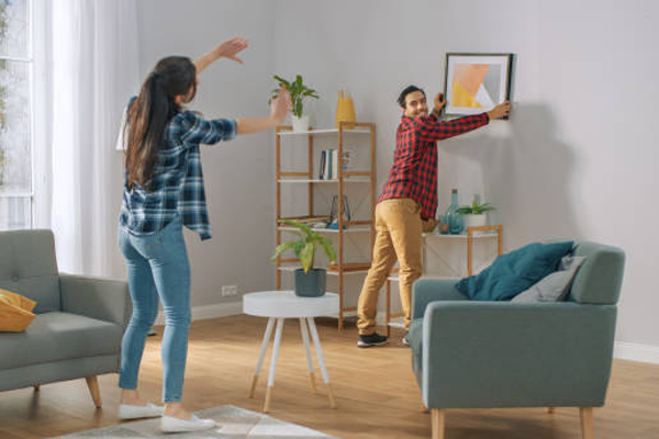 Woman guiding man on hanging up a picture in their home