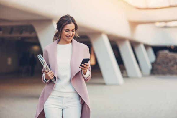 Working woman walking and smiling while looking at her phone