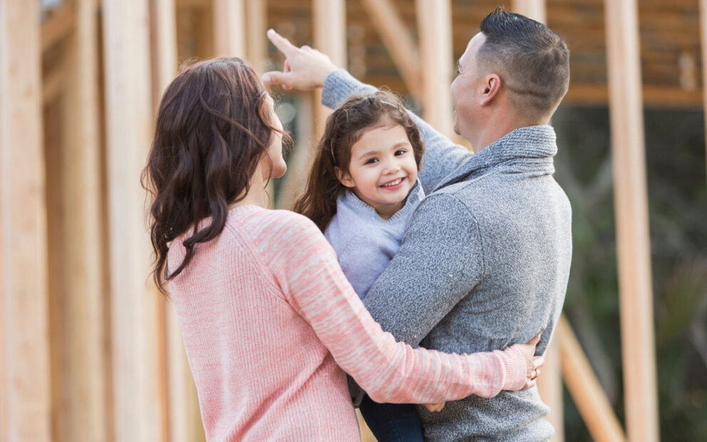 Couple holding their child wild looking at home construction