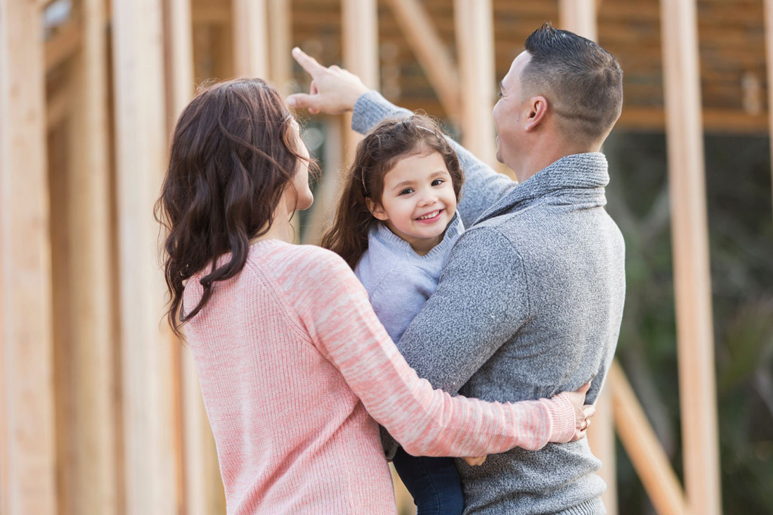 Couple holding their child wild looking at home construction