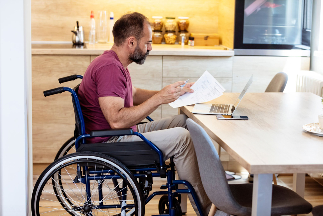 Man in wheelchair reviewing documents at desk