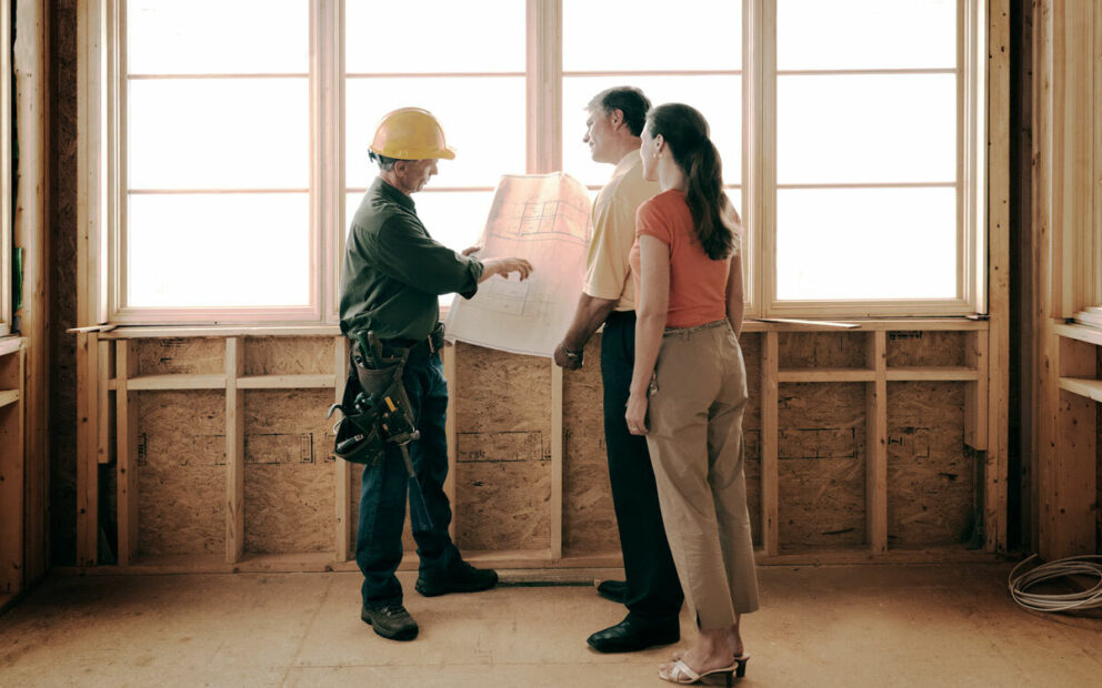 Man and woman couple reviewing contruction plans with builder