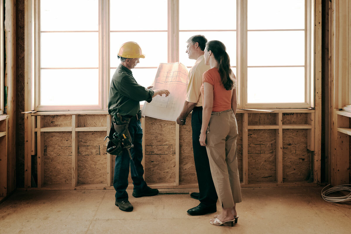 Man and woman couple reviewing contruction plans with builder