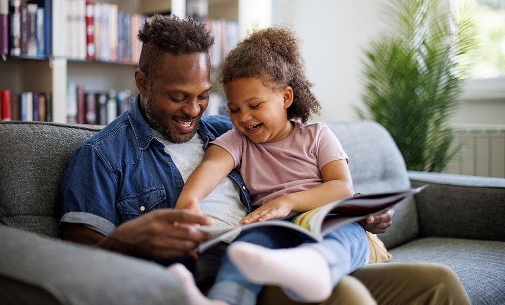Dad reading to his daughter while she sits on his lap