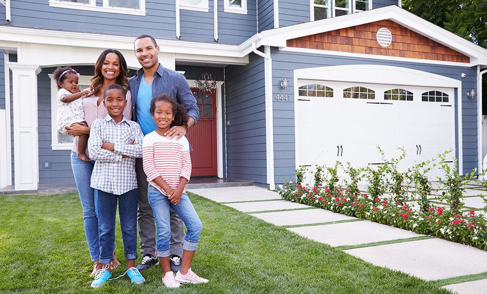 Happy family standing in front of new home