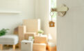 Key unlocking door to new home with move-in boxes neatly stacked in living room