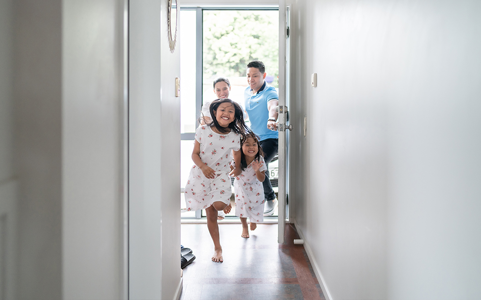 Couple and their children excitedly running inside new home