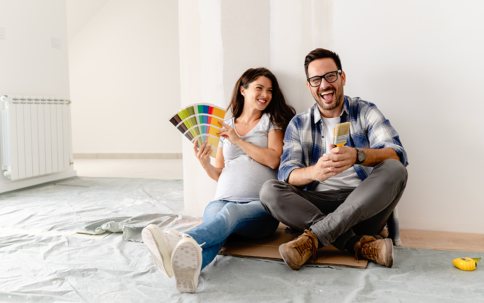 Man and woman couple sitting on floor in new home while looking at color samples