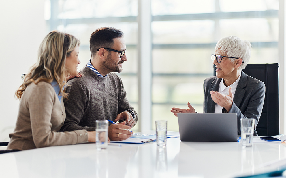Man and woman couple sitting at desk talking with financial advisor