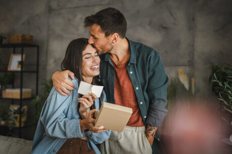 Couple smiling and embracing while sitting on couch together