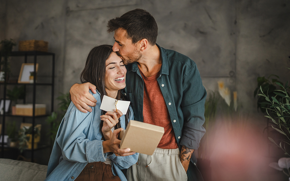 Couple smiling and embracing while sitting on couch together
