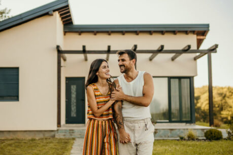 Couple walking and smiling together in front of new home
