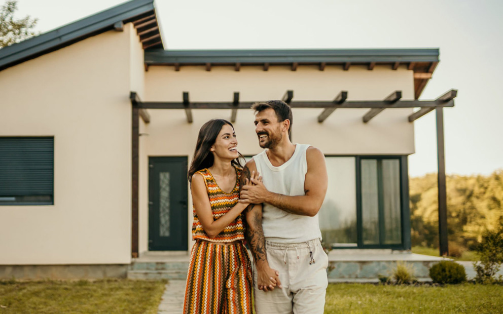 Couple walking and smiling together in front of new home