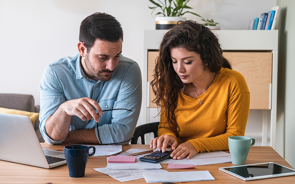 Couple sitting together while they review financial documents