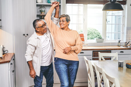 Older couple smiling and dancing in kitchen of home