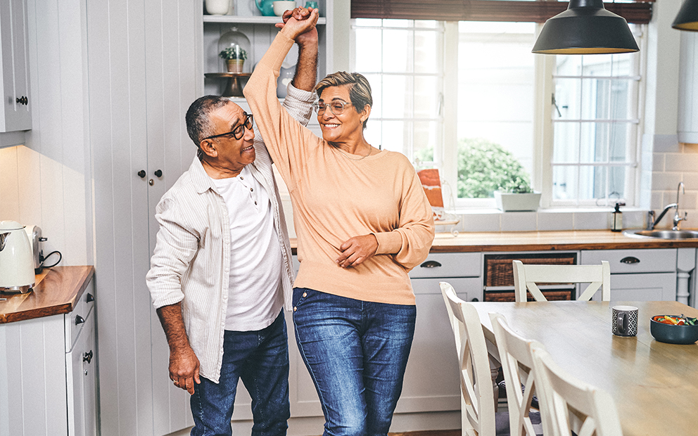 Older couple smiling and dancing in kitchen of home