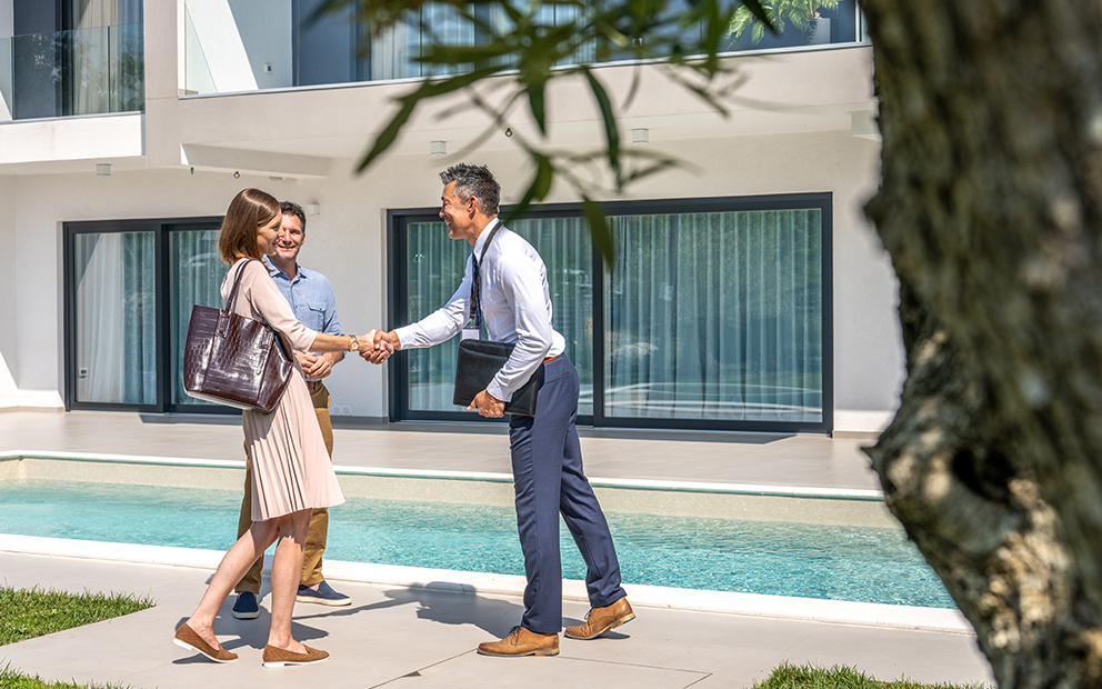 Realtor shaking hands with couple outside home