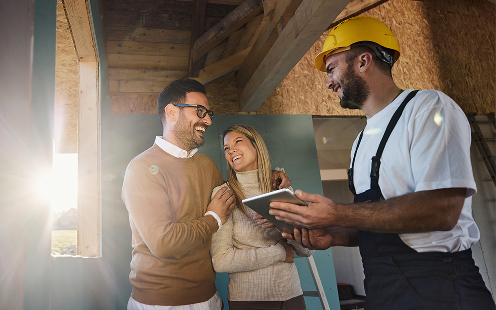 Couple speaking with builder inside home