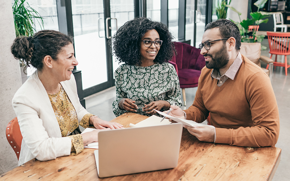 Man and woman couple speaking with advisor while sitting at a table