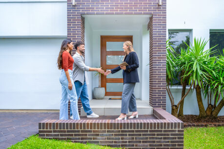 Couple shaking hands with realtor outside of home
