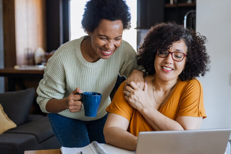 Couple smiling together while they look at information on laptop