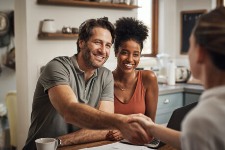 Couple speaking and shaking hands with realtor
