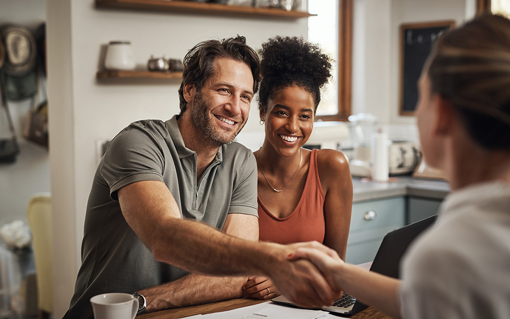 Couple speaking and shaking hands with realtor