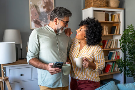 Couple looking at each other while they smile and discuss finances in home