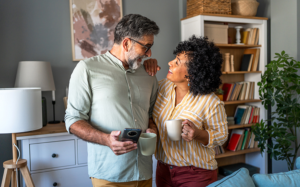 Couple looking at each other while they smile and discuss finances in home