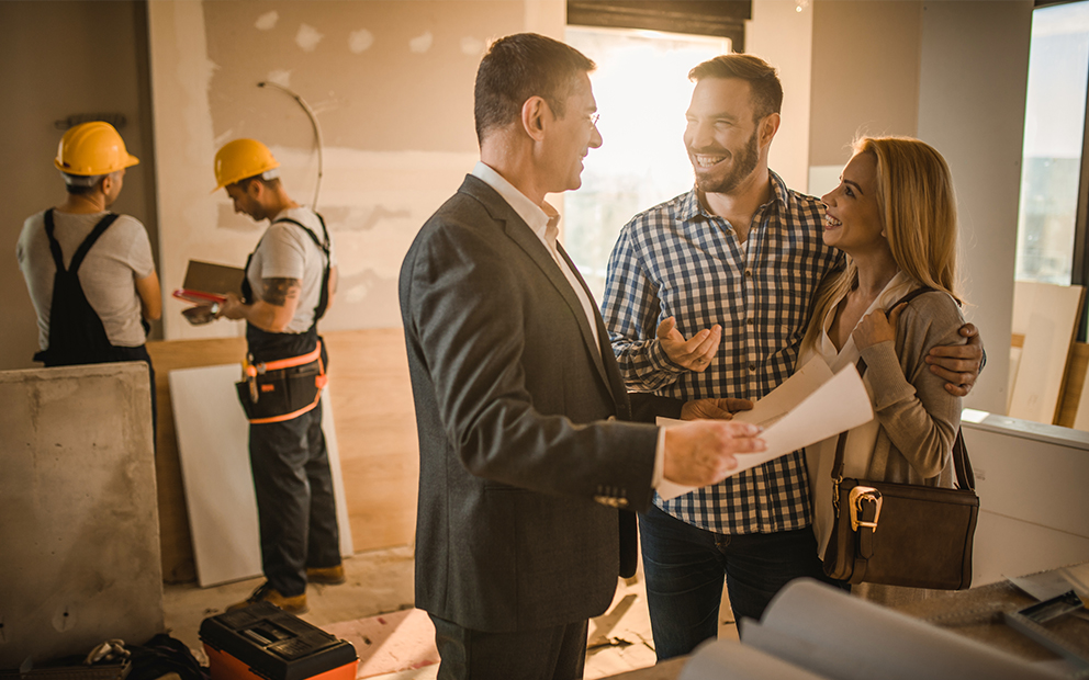 Couple talking to realtor in home while it is under construction