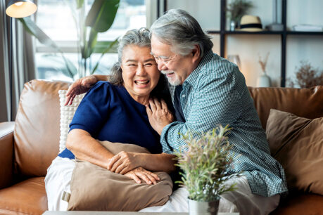 Older couple smiling and being affectionate with each other while sitting on the couch