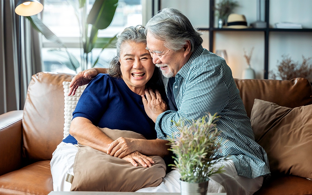 Older couple smiling and being affectionate with each other while sitting on the couch
