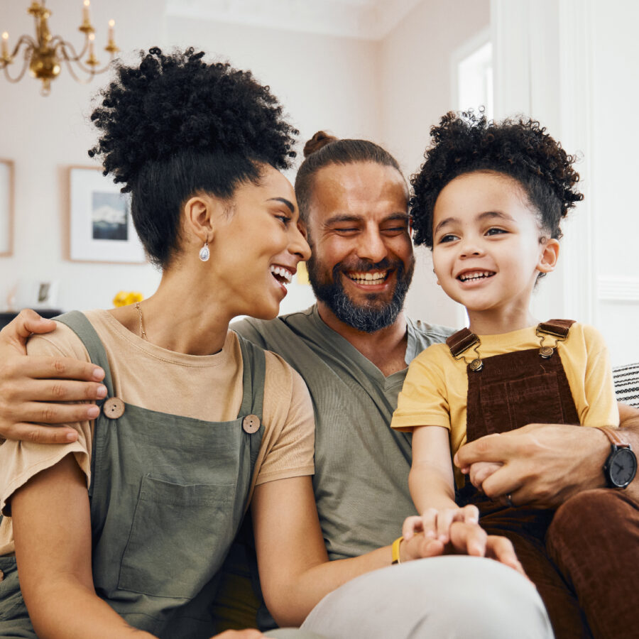 Smile, relax and an interracial family on the sofa for conversation, love and bonding. Happy, house and a mother, father and a boy child on the couch for talking, care and together for communication