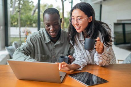 Man and woman couple looking at laptop together while they sit at kitchen table