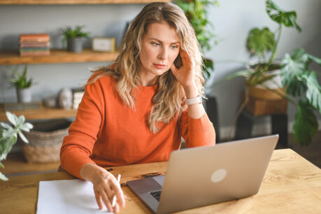 Woman with concerned expression as she looks at laptop screen