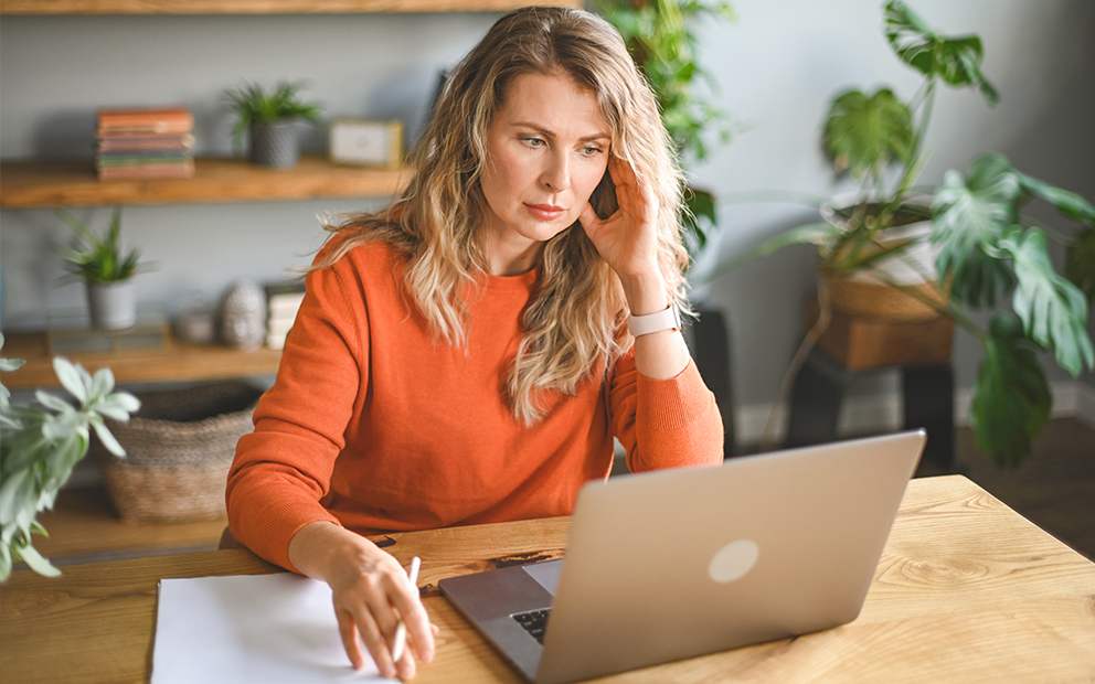 Woman with concerned expression as she looks at laptop screen
