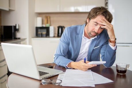 Man stressed out while reviewing finances at home kitchen table