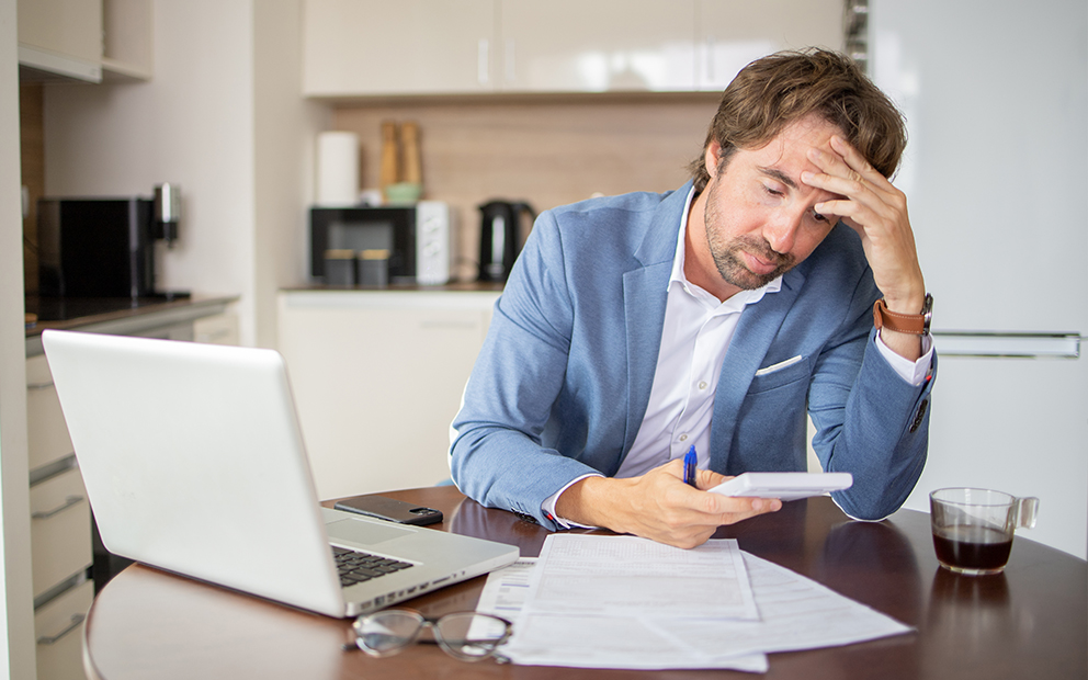 Man stressed out while reviewing finances at home kitchen table
