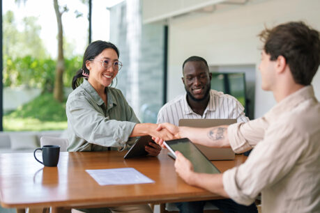 Couple shaking hands and speaking with advisor inside their home